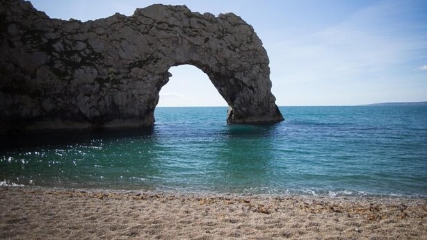 A natural rock arch formation over a calm sea. - Tavern Way (Wareham)