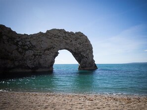 A natural rock arch formation over a calm sea. - Tavern Way (Wareham)