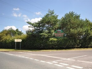Una señal de tráfico para Monkey World con un logo verde y texto, y una señal direccional que indica Monkey World a la derecha.