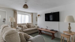A living room with a sofa, a coffee table, a TV, and lamps. - Tavern Way (Wareham)