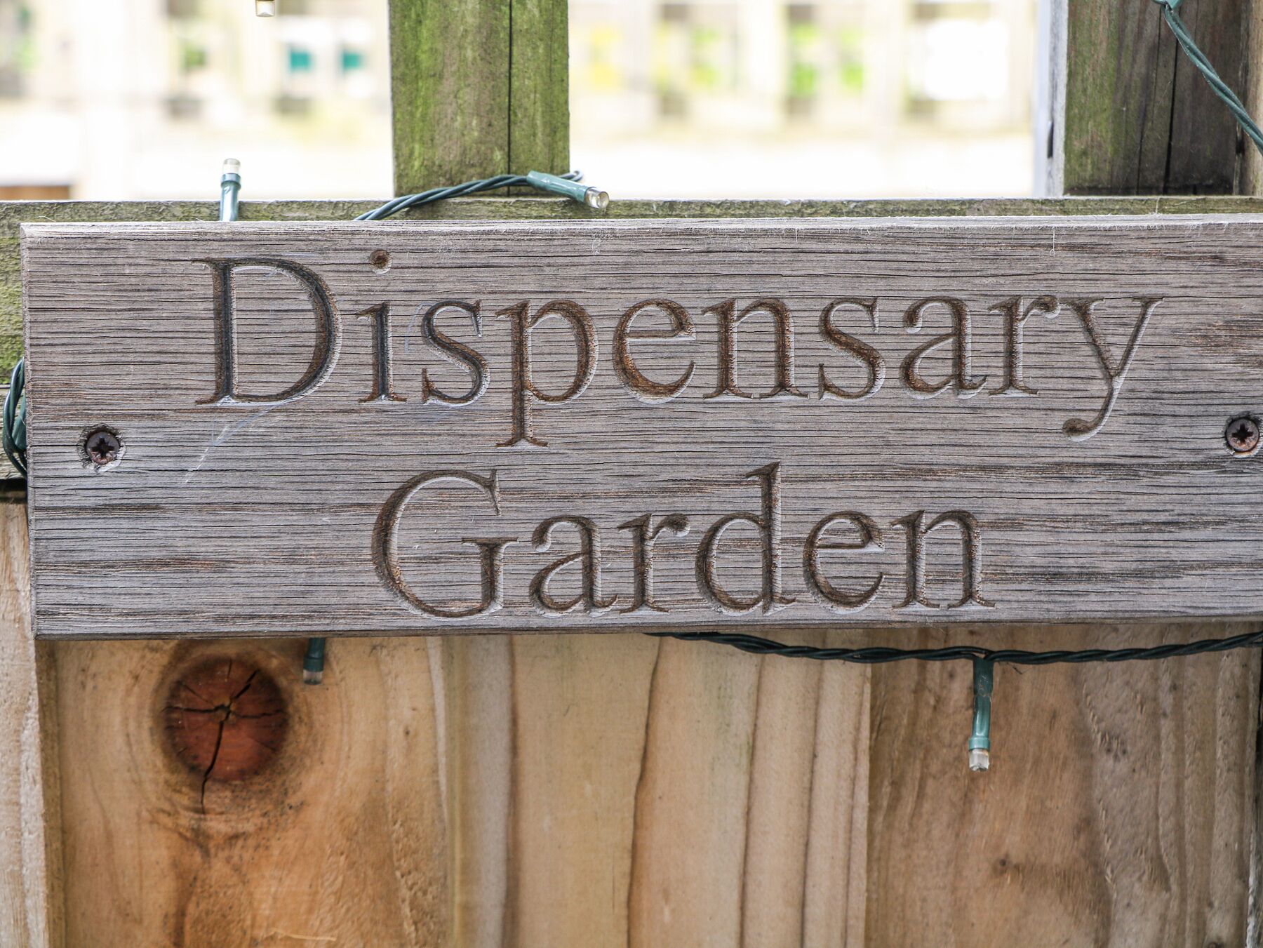 Une enseigne en bois sur laquelle sont gravés les mots « Jardin de la pharmacie ».
