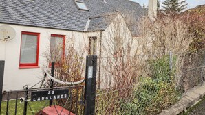 Une maison avec un toit en pente, une antenne parabolique et une cour clôturée.
