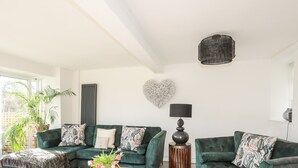 A modern living room with two green sofas, a wooden coffee table, and a decorative lamp. - Ty Mawr (Menai Bridge)