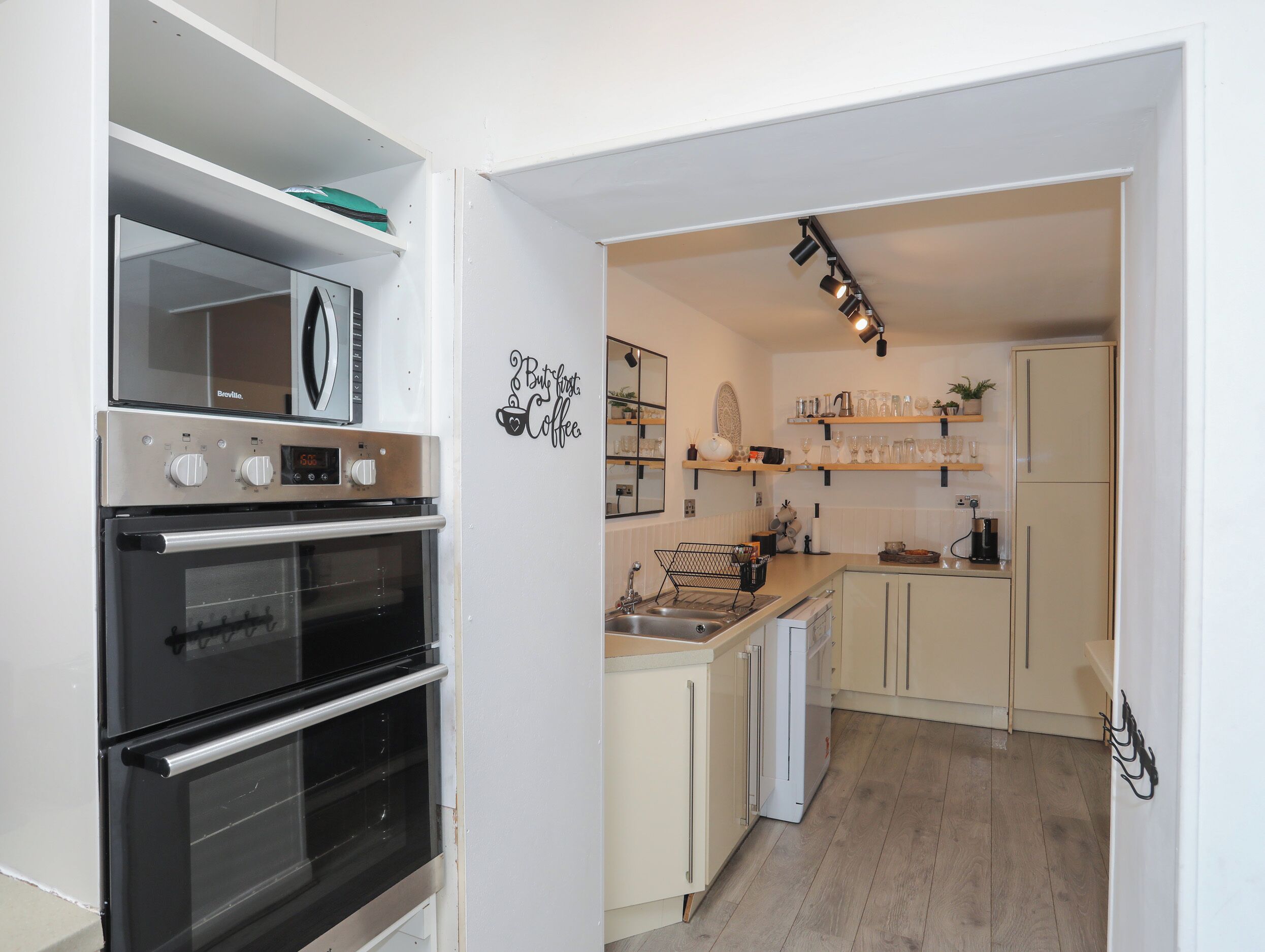 Una cocina moderna con electrodomésticos de acero inoxidable, estantes de madera y decoración temática de café.
