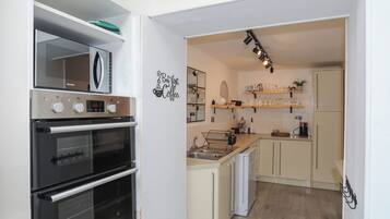 Una cocina moderna con electrodomésticos de acero inoxidable, estantes de madera y decoración temática de café.