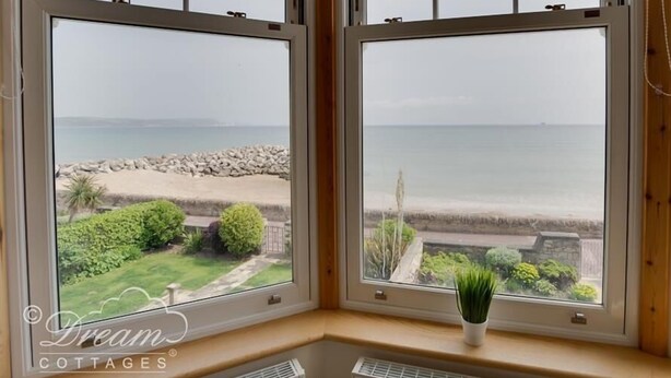 A room with two large windows overlooking a beach. - Beach View Apartment 3 (Weymouth)