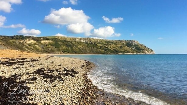 A beach with pebbles and a clear blue sky.