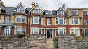 A row of terraced houses with stone walls and bay windows.