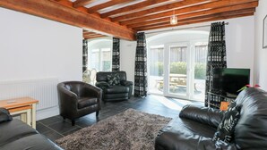 A living room with a fireplace, leather sofas, a coffee table, and a TV. - Hafod (Caernarfon)