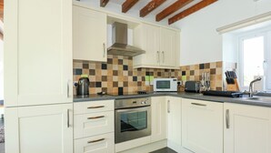A modern kitchen with white cabinets, a microwave, a toaster, and a sink. - Hafod (Caernarfon)