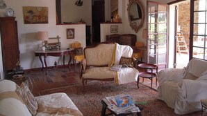 A traditional living room with a sofa, armchairs, a coffee table, and a fireplace. There is a wooden cabinet and a mirror on the wall.