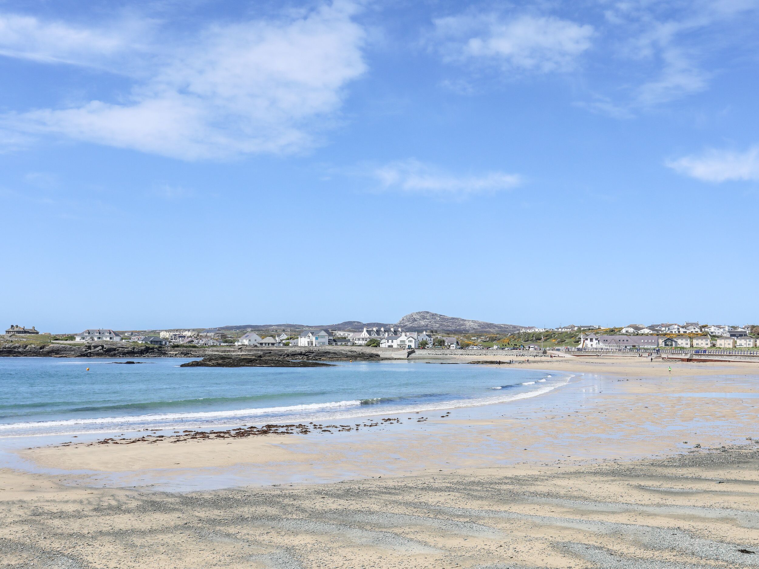 Ein Küstenort mit Sandstrand, ruhiger See und Häusern entlang der Küste.