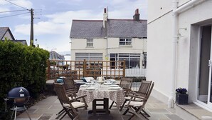 A patio with a round table and four chairs, surrounded by a white fence. - West View (Rhosneigr)