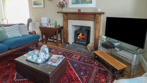 A living room with a sofa, a fireplace, a TV, and a coffee table with cups and a magazine. - West View (Rhosneigr)