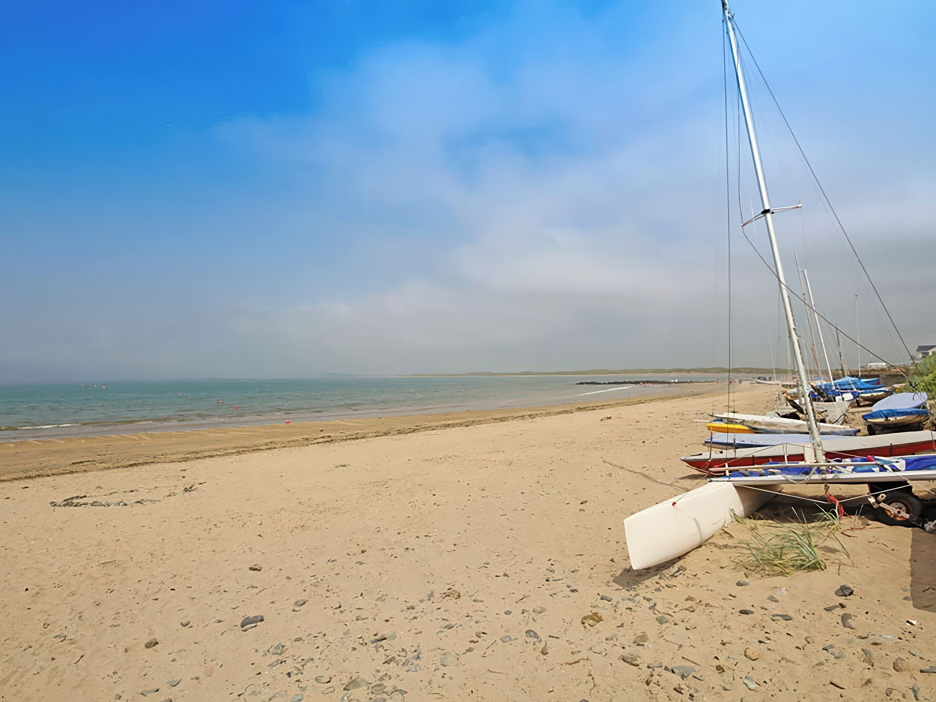 A beach with boats and a clear sky.