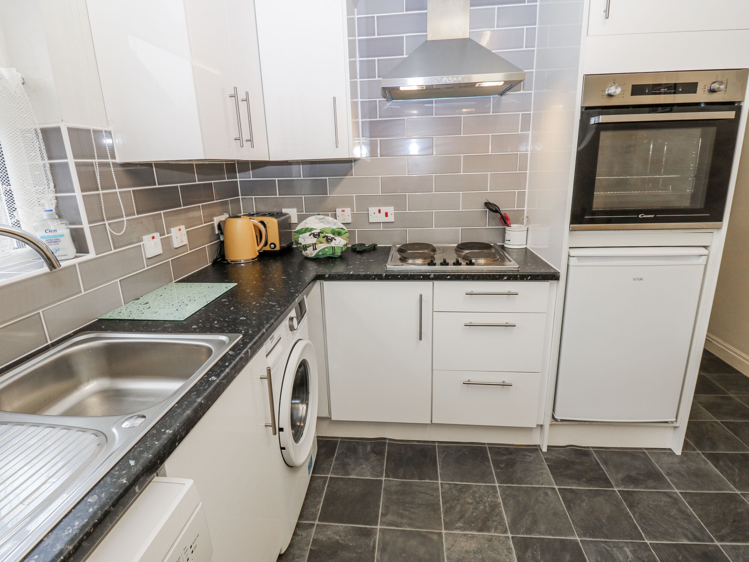 A compact kitchen with a washing machine, a stove, and a built-in oven.