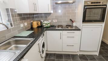 A compact kitchen with a washing machine, a stove, and a built-in oven.