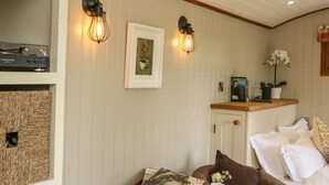 A cozy room with a wooden cabinet, a framed picture, and a small table with a magazine and cups.
