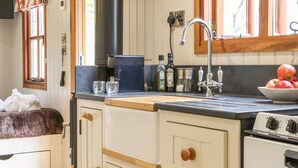 A kitchen with a stove, sink, and wooden cabinets.
