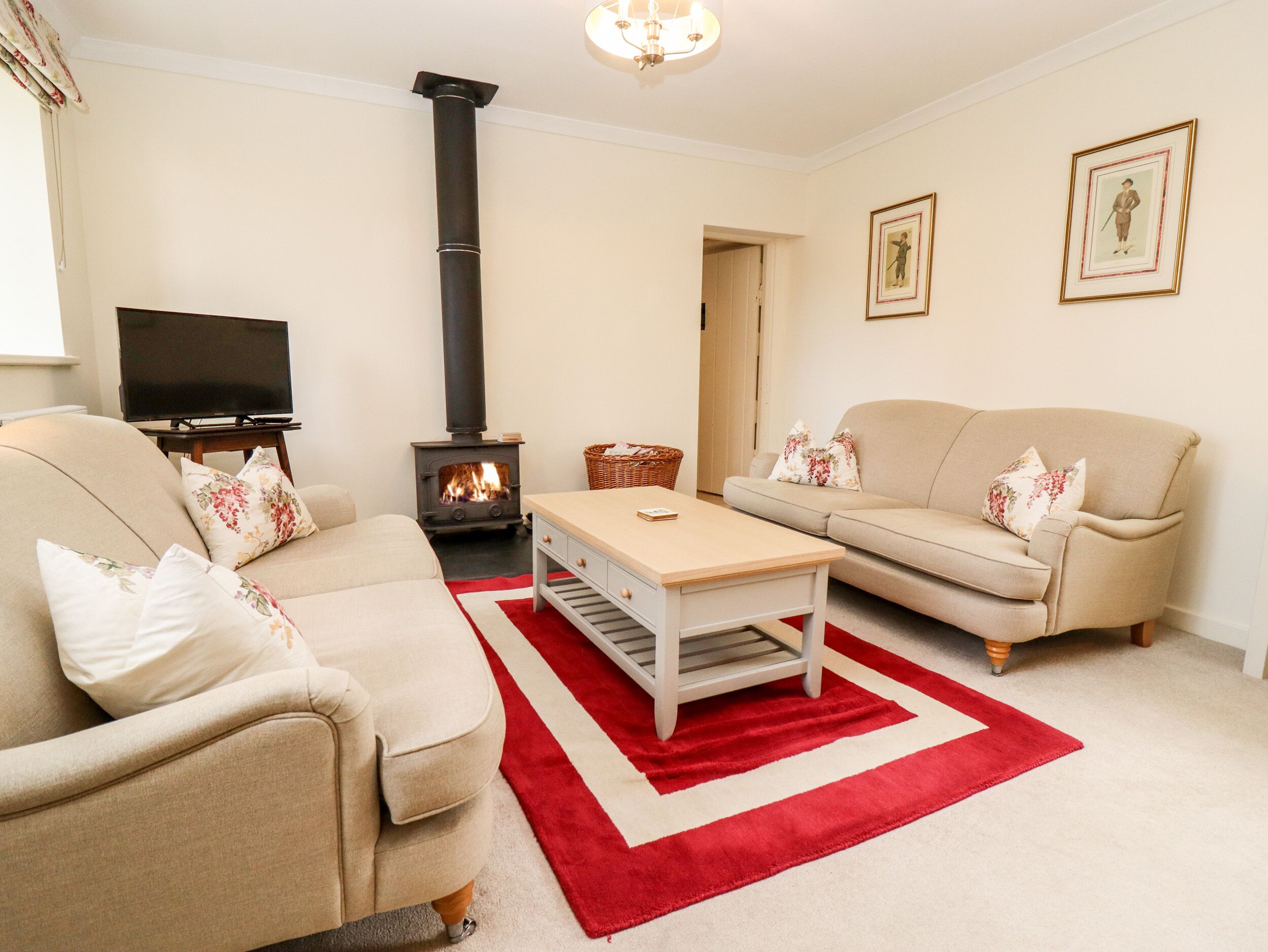 A living room with a beige sofa, a red and white rug, a television, and a fireplace.