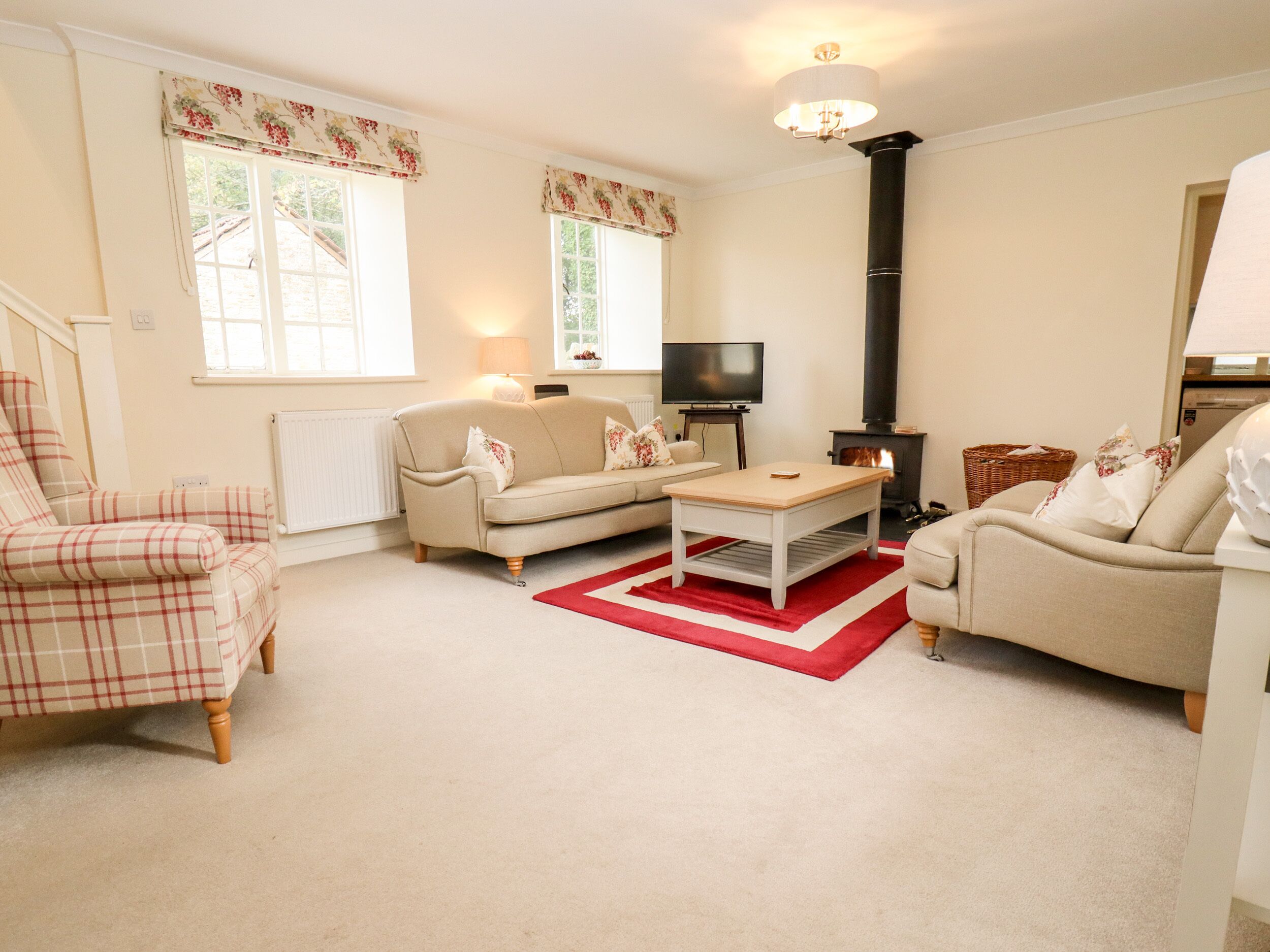 A cozy living room with a sofa, armchair, and coffee table, a fireplace, and a television.