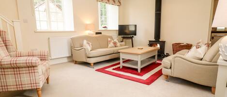 A cozy living room with a sofa, armchair, and coffee table, a fireplace, and a television.