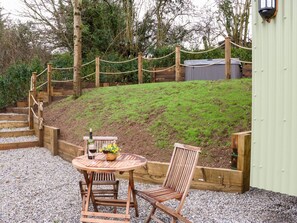 A wooden outdoor seating area with a table and chairs, surrounded by a rope fence and a wooden deck.