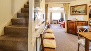 Eine Treppe führt zu einem Wohnbereich mit einer Couch, einem Holzkabinett und einem Gemälde an der Wand.