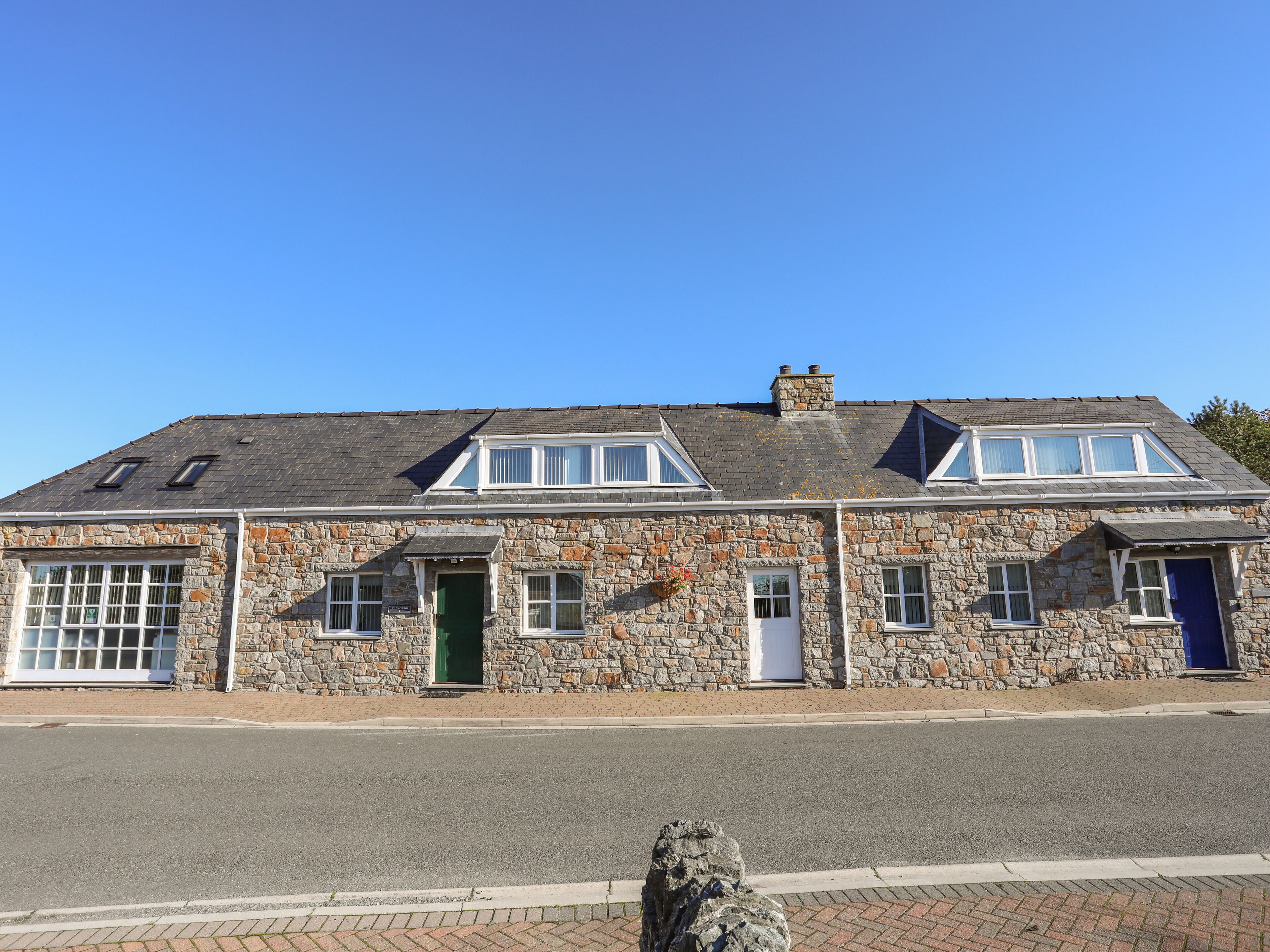 Un bâtiment en pierre avec un toit à pignon, deux lucarnes et une porte verte.