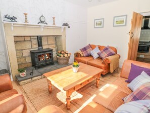 A cozy living room with a fireplace, a sofa set, a wooden coffee table, and a basket of firewood. - Appletree (Alnwick)