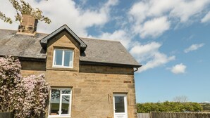 Une maison en pierre avec un toit à pignon, une porte d’entrée et une fenêtre.