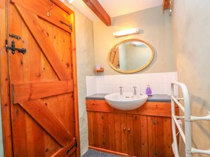 Bathroom features a sink, mirror, and shelf with a cup.