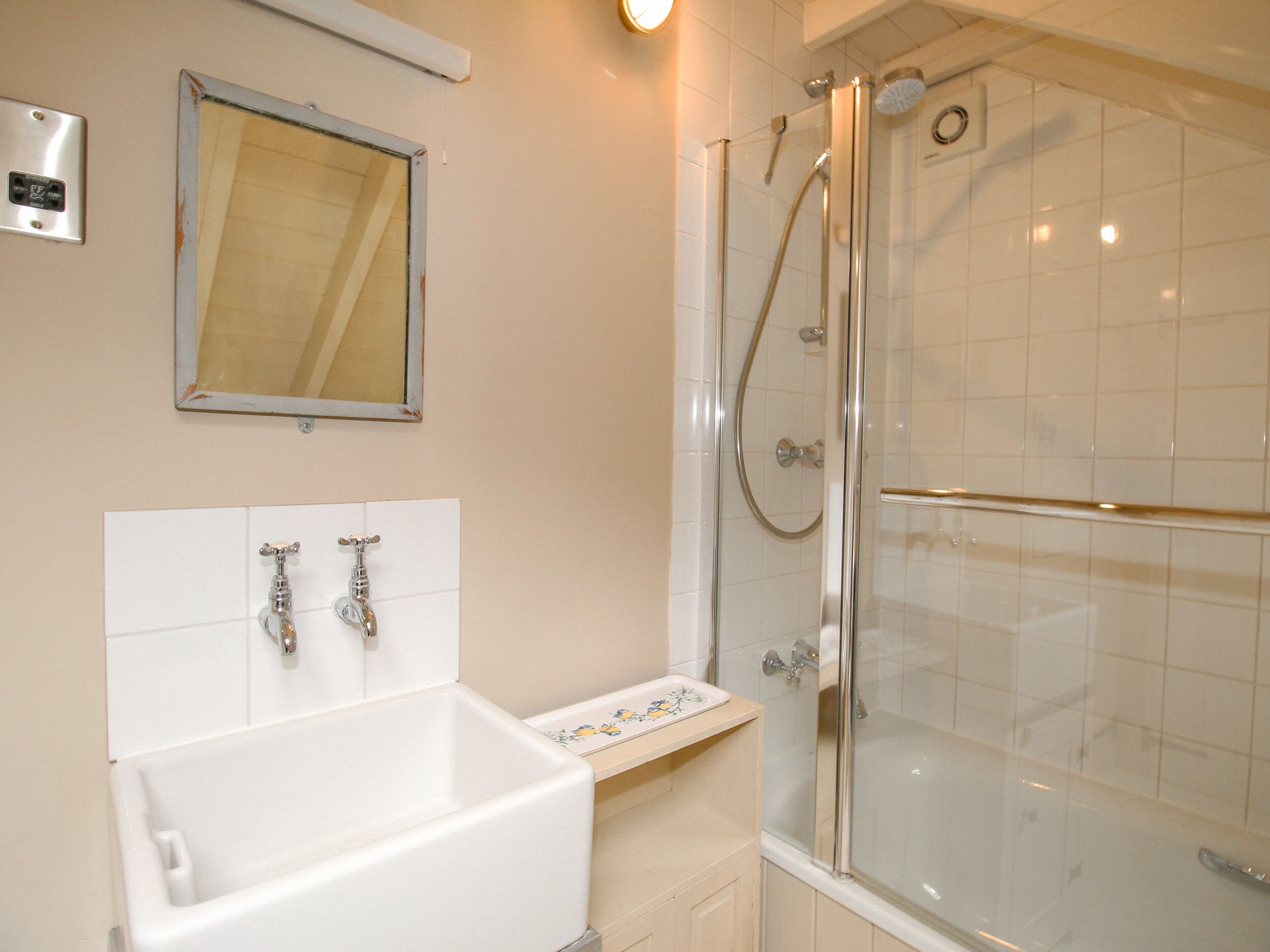 Un baño con una bañera blanca, ducha con mampara de vidrio y un espejo en la pared.