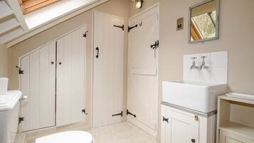 Une salle de bain avec un puits de lumière, des meubles blancs, des toilettes, un lavabo et un miroir.
