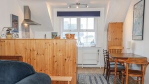 Eine kompakte Küche mit Holzschränken, ein Essbereich mit Tisch und Stühlen sowie ein großes Fenster mit Blick auf die Stadt.