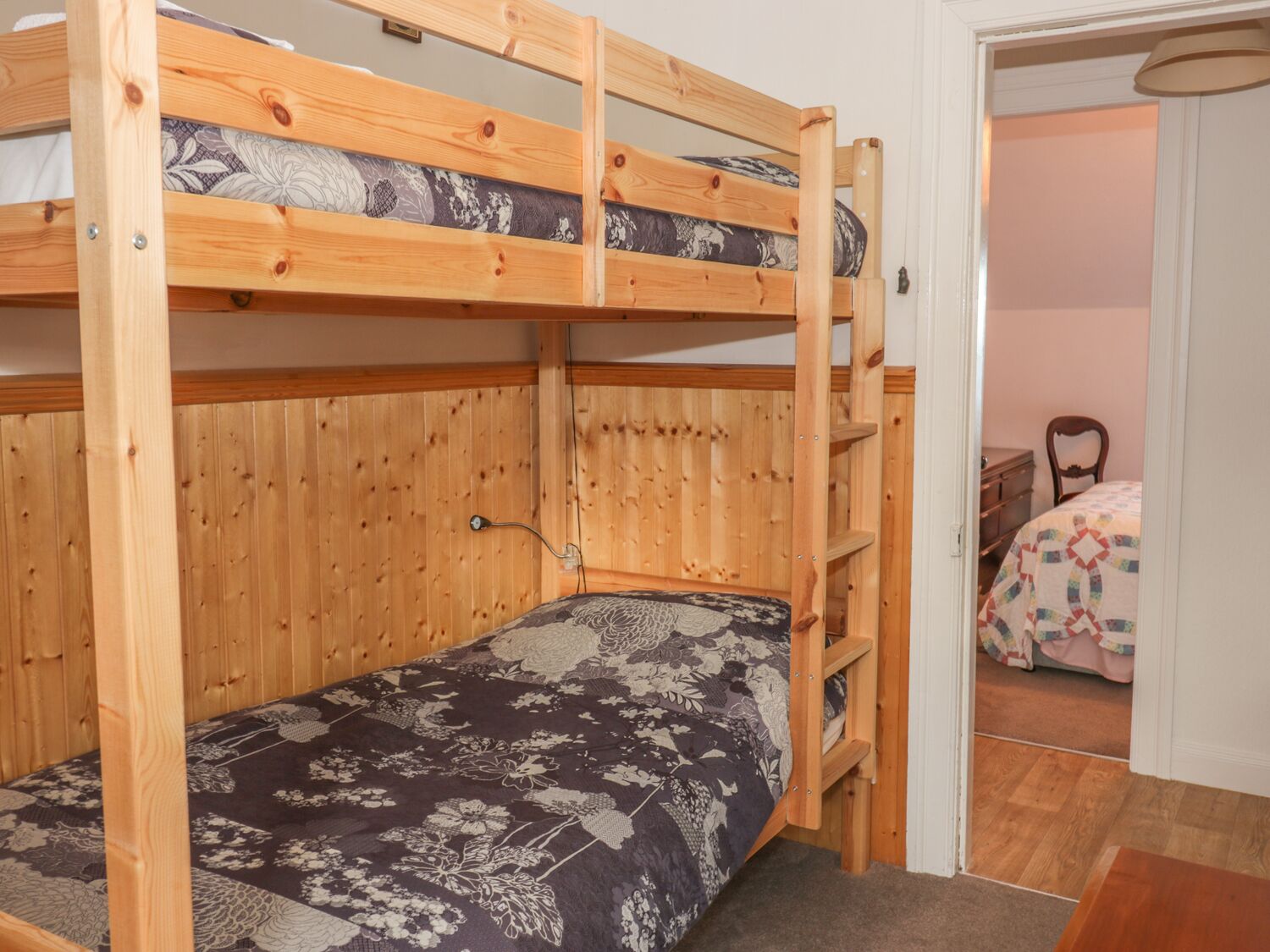 A bunk bed with a floral-patterned bedspread and a wooden headboard.
