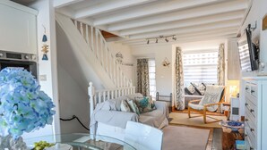 A cozy room with a bed, a chair, a table with a teapot, and a staircase. - St Agnes (Porthmadog)
