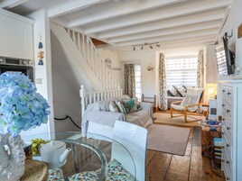 Una habitación acogedora con una cama, una silla, una mesa con tetera y una escalera.