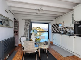 Una cocina con vistas a un lago, una mesa de comedor con sillas y un refrigerador.