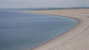 A coastal beach with a wide sandy shore and calm waters.