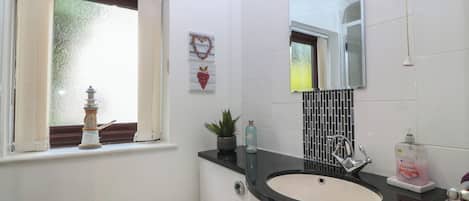 Et badeværelse med toilet, vask og vindue.