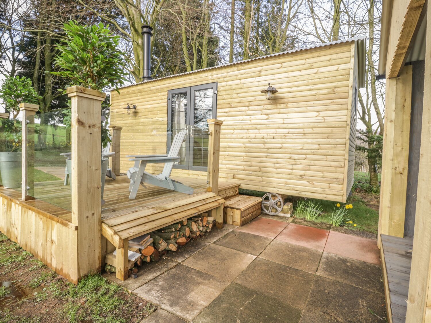 A wooden cabin with a deck, a chair, and a window.