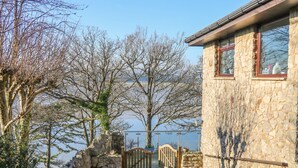A stone building with a wooden gate and a view of a body of water. - Shady Bowers (Carnforth)