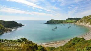 Un paysage côtier avec une plage, des bateaux et des falaises.