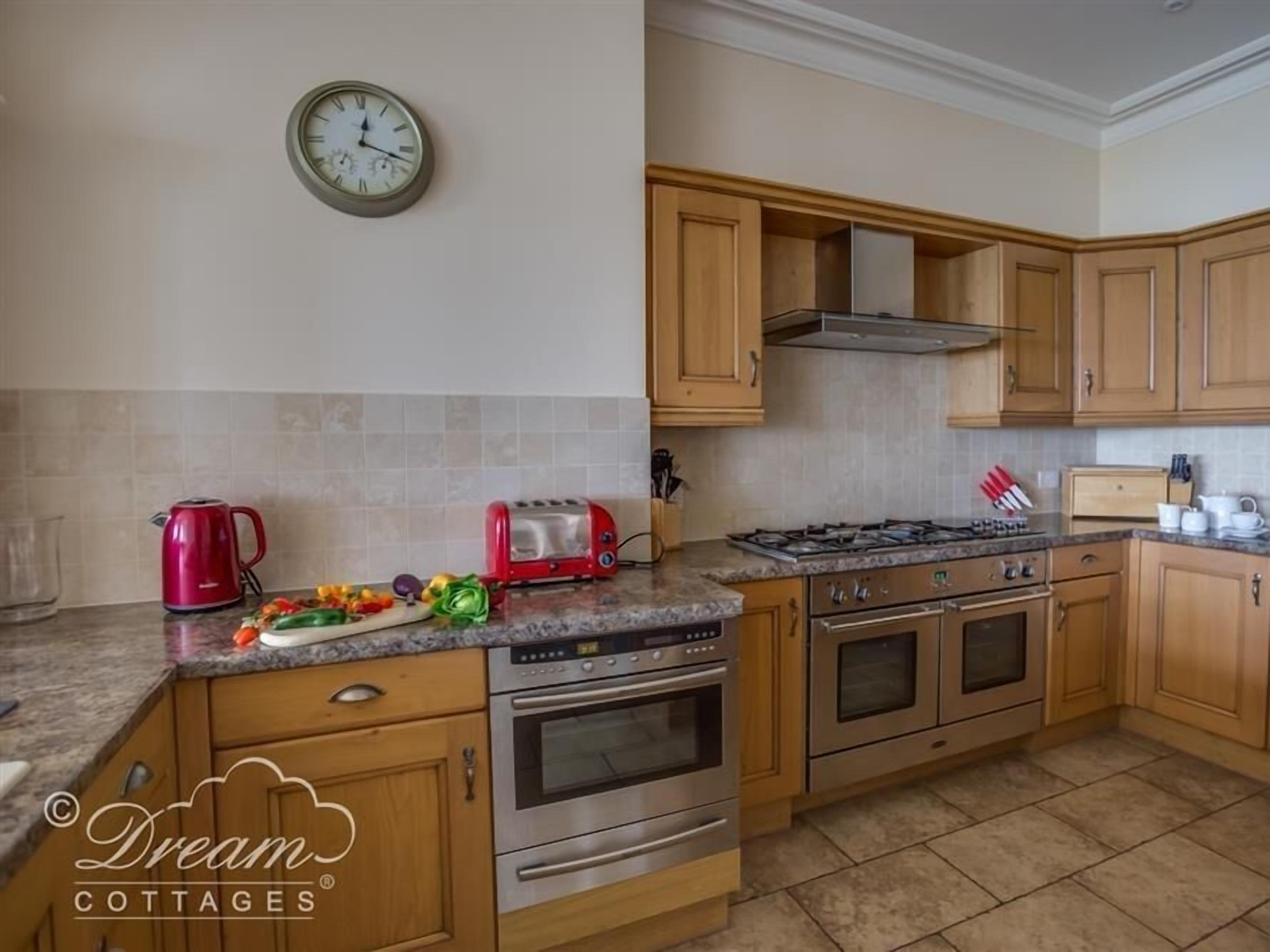 Una cocina con armarios de madera, estufa a gas, horno, tostadora y hervidor.