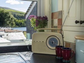 Una radio d'epoca su un bancone della cucina, con vista su un lago e delle colline attraverso una finestra.