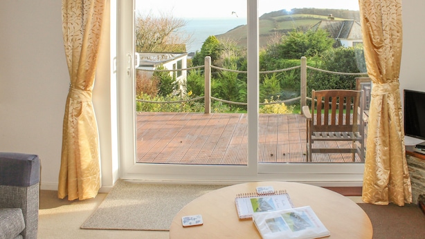 A room with a view of the sea, a wooden deck, and a chair. - Brambles (St Austell)