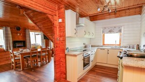 A cozy cabin-style kitchen with wooden floors, white cabinets, and a dining area with a table and chairs.