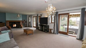A living room with a fireplace, a television, and a balcony with a hot tub. - Shatterford Lakes (Bewdley)