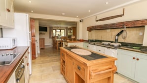 A kitchen with a central island, wooden cabinets, a built-in oven, and a rustic backsplash.